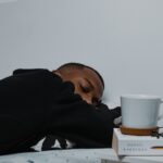 수면 혁명, ‘마이크로 슬립’부터 AI 수면 관리까지…최신 트렌드로 건강하게 자는 법 a man sleeping on a bed next to a stack of books