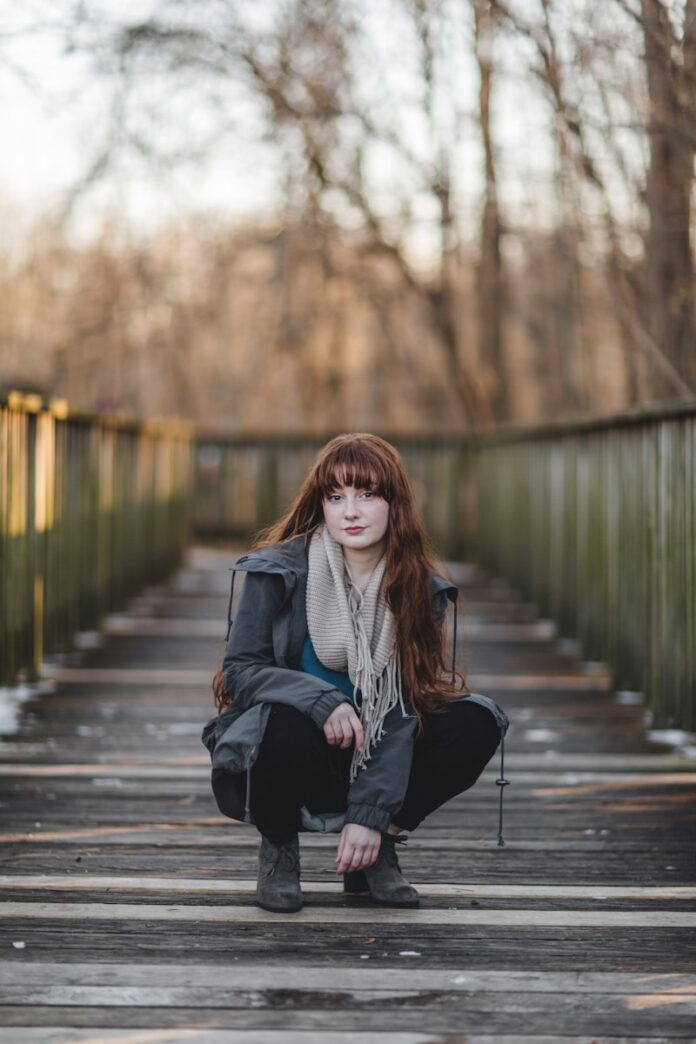 Photo by Caleb Lucas woman sitting on wooden bridge