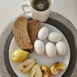 바쁜 일상 속 ‘현명한 식단’이 뜬다… 작은 변화로 시작하는 건강한 한 끼 A white plate topped with sliced apples and a cup of coffee