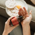 영양제, 어떻게 똑똑하게 챙길까? 한국인의 일상을 위한 실천 팁 person holding red bottle