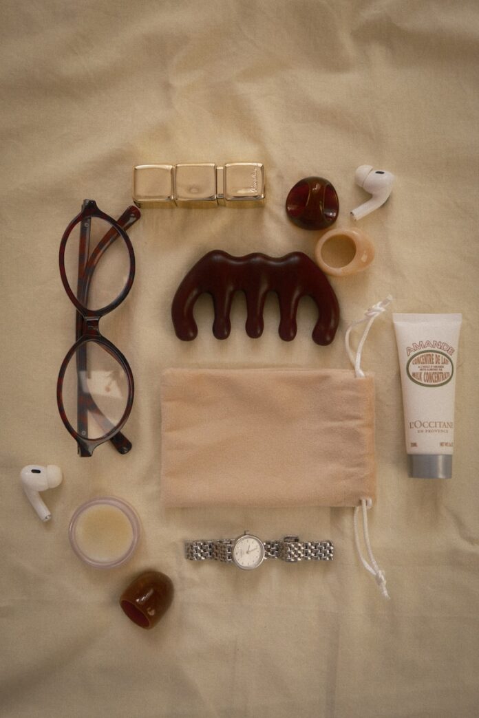 Photo by Katya Azimova Eyeglasses, comb, lotion, watch, and earbuds arranged flat lay.
