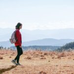 MZ세대부터 시니어까지, ‘마음챙김 걷기’로 삶의 질 높이기 a man with a backpack walking across a dry grass covered field