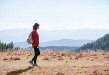 MZ세대부터 시니어까지, ‘마음챙김 걷기’로 삶의 질 높이기 a man with a backpack walking across a dry grass covered field